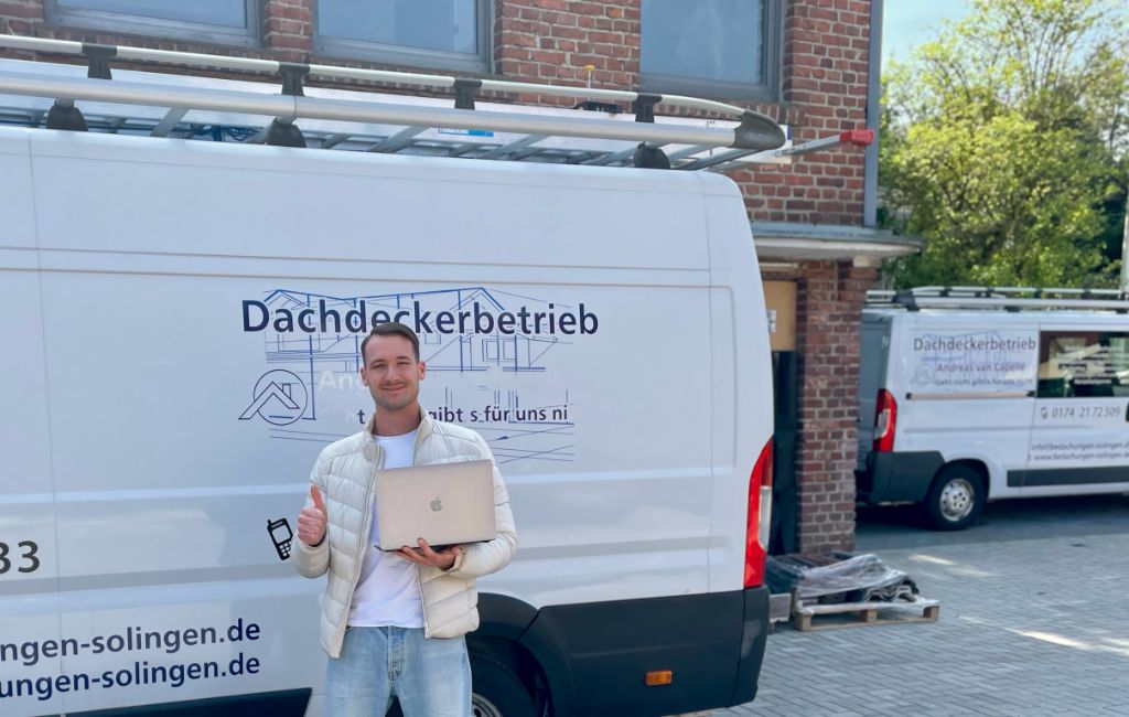 Dean Aaron Budde mit Laptop vor dem Firmenfahrzeug von Bedachungen Krüger