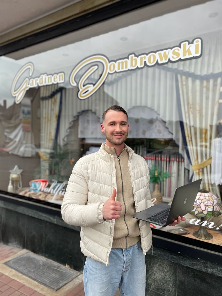 Dean Aaron Budde vor dem Laden von Gardinen Dombrowski mit Laptop